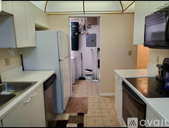 A kitchen with white cabinets and a black fridge.