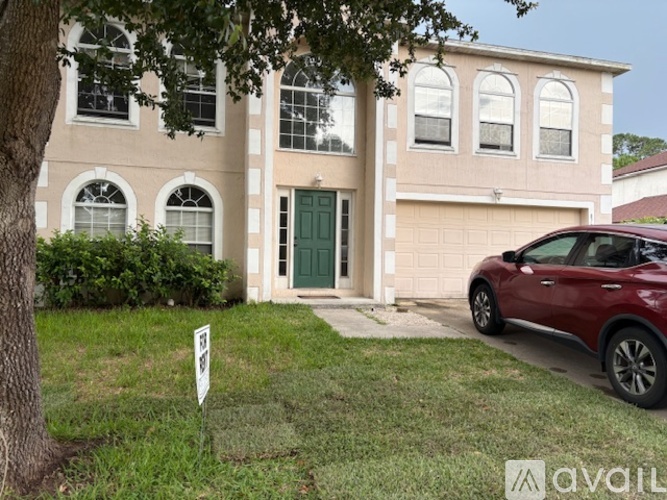 A two-story house with a garage and a car parked in front.