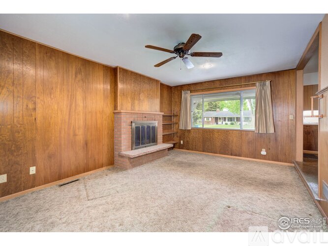 A living room with wood paneling and a fireplace.