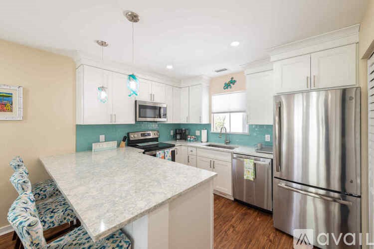 A kitchen with a white counter top and a stainless steel refrigerator.