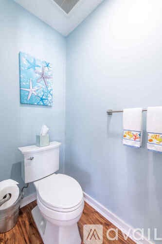 A white toilet with a white tank and a painting of a starfish on the wall.