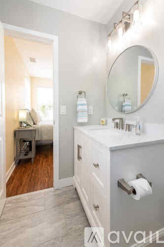A bathroom with a white vanity and a round mirror.