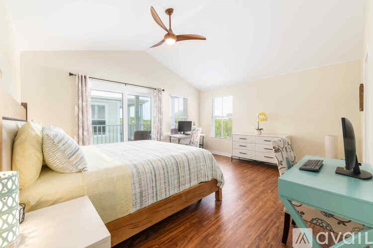 A bedroom with a bed, dresser, and a ceiling fan.