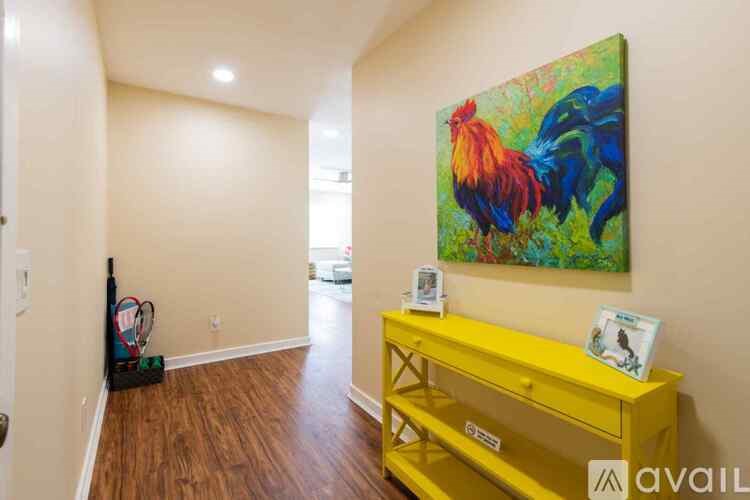 A yellow desk with a painting of a rooster on the wall.