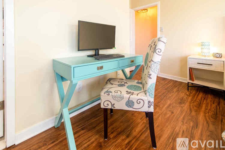 A blue desk with a black monitor and a patterned chair.