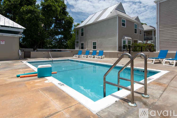 A pool with a metal ladder and blue chairs.