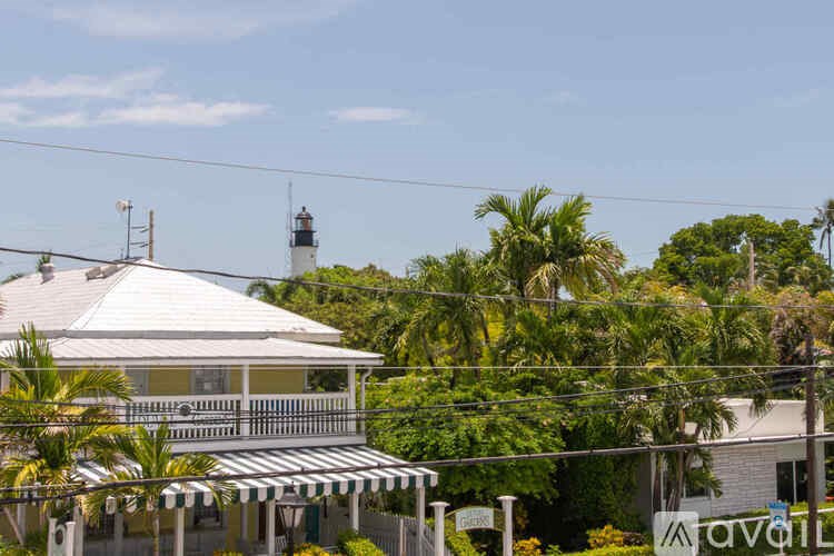 A house with a white roof and a lighthouse in the background.