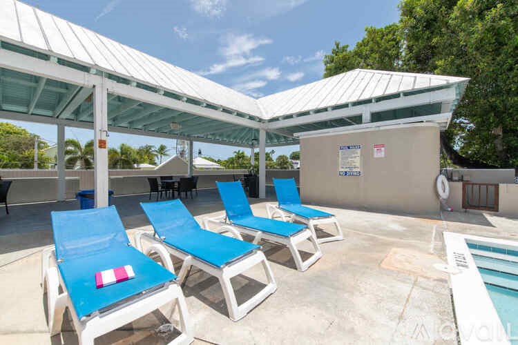 A pool area with blue lounge chairs and a white roofed pavilion.