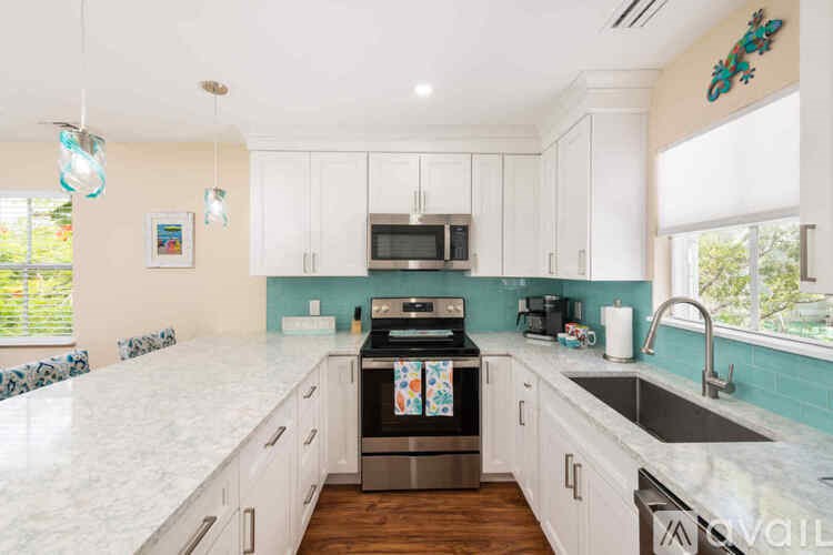 A kitchen with white cabinets and a marble countertop.