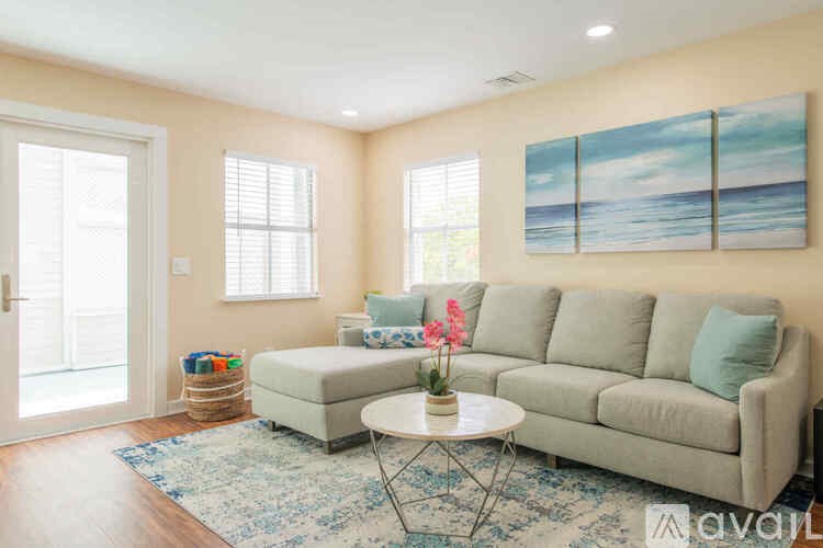 A living room with a grey couch, a coffee table, and a painting on the wall.