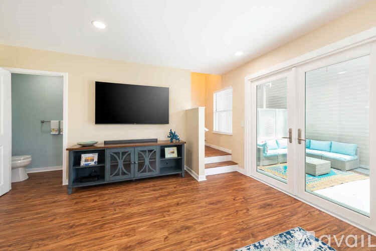 A living room with a television and a glass door leading to a balcony.