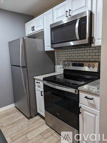 A kitchen with a stainless steel refrigerator, microwave, and oven.