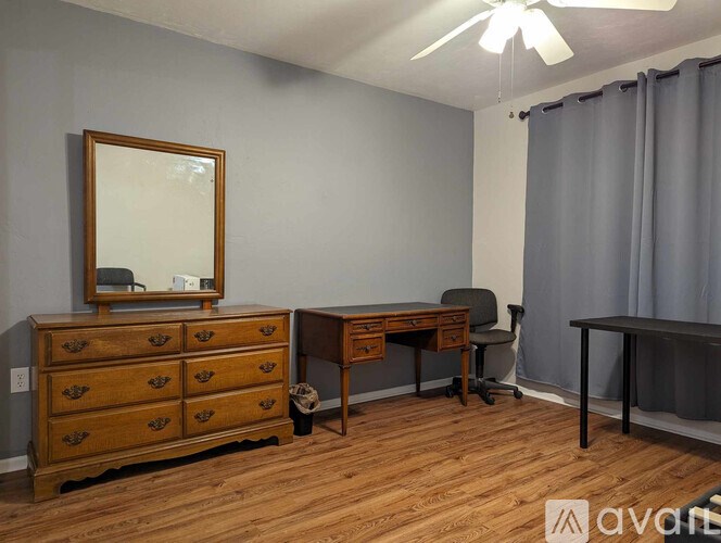 A room with a wooden dresser, a mirror, a desk, and a chair.