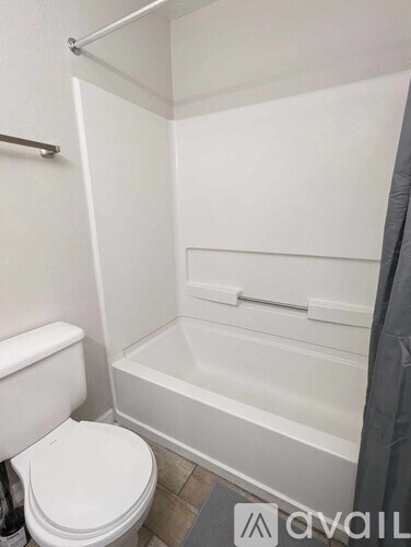 A white toilet sits next to a white bathtub in a small bathroom.