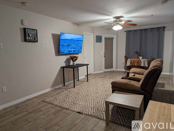 A living room with a flat screen TV and a rug on the floor.