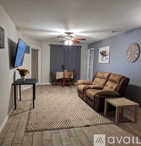 A living room with a brown couch, a small table, and a television.