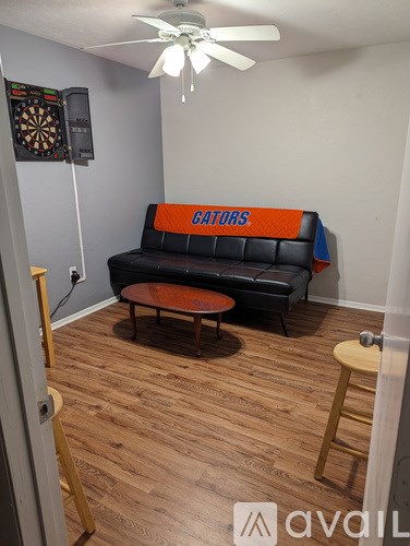 A room with a couch and a dartboard on the wall.