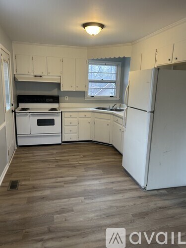 A kitchen with white appliances and wooden floors.