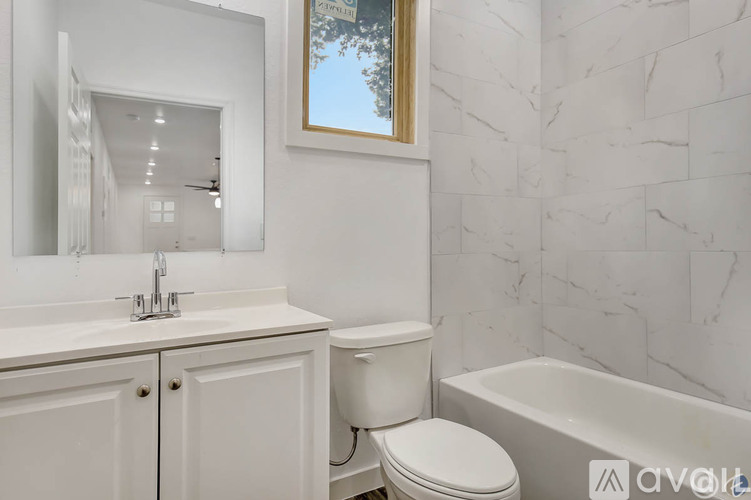 A white bathroom with a marble wall and a toilet.