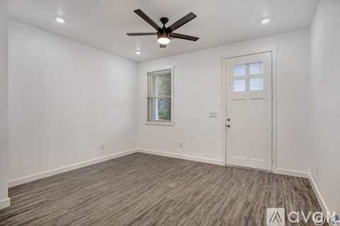 A room with a ceiling fan and a window with a white door.