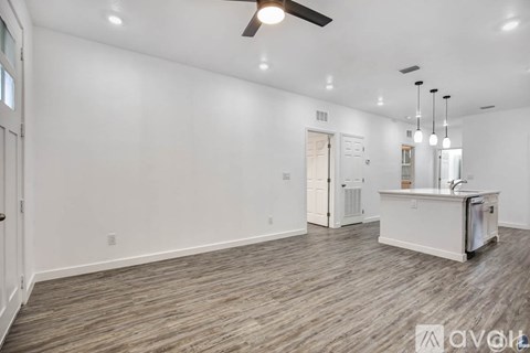 A spacious room with a kitchenette and a ceiling fan.