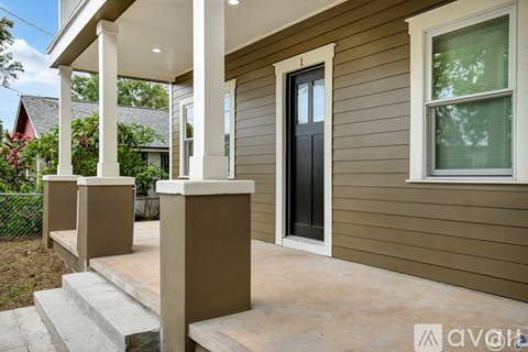A house with a brown siding and a black door is for sale.