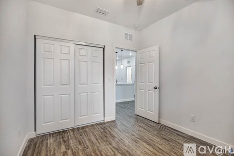 A room with a white door and a wooden floor.