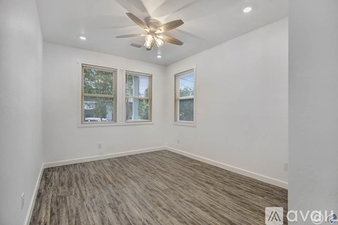 A room with a ceiling fan and wood flooring.