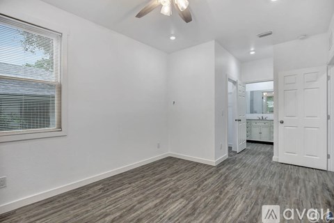 A room with a ceiling fan and a window with blinds.