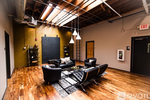 A living room with a black couch and a wooden floor.