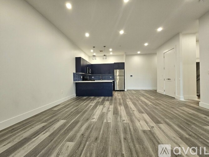 A spacious room with wooden flooring and a kitchenette in the corner.