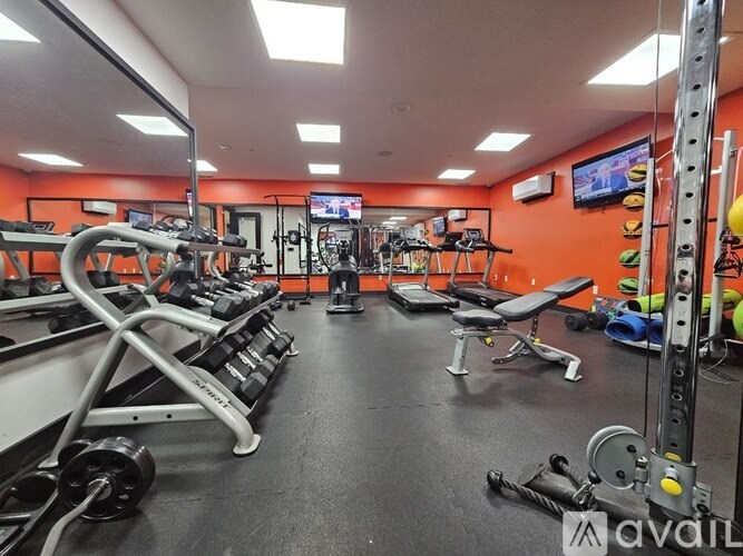 A gym with a variety of equipment including treadmills, weights, and exercise machines.