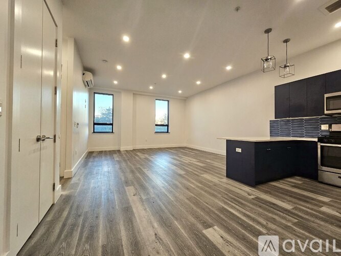 A spacious room with wooden flooring and a kitchen area with a stove and oven.