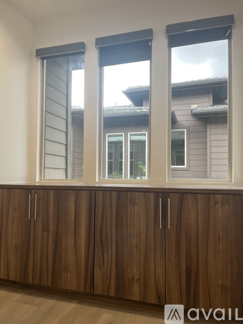 A brown wooden cabinet with three doors and two drawers is in front of a window.