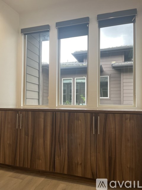 A brown wooden cabinet with three doors and two drawers is in front of a window.