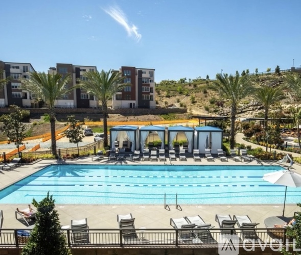 A large swimming pool with lounge chairs and umbrellas in front of a resort.
