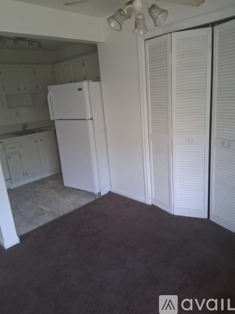 A white refrigerator in a kitchen with white cabinets.
