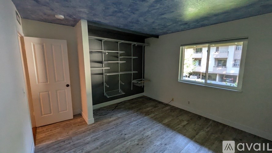 A woman is standing in a doorway with a table and chairs in the room.