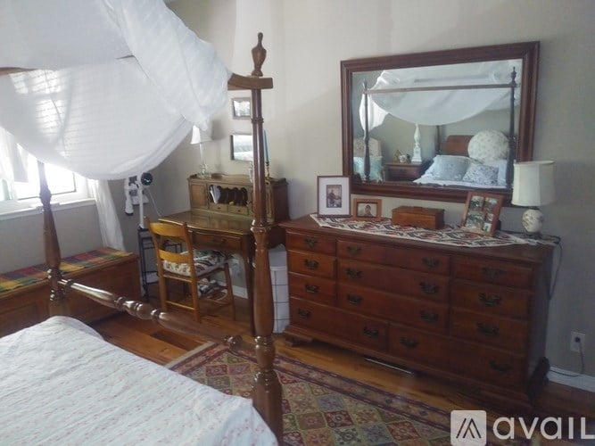 A bedroom with a canopy bed, a dresser, and a mirror.
