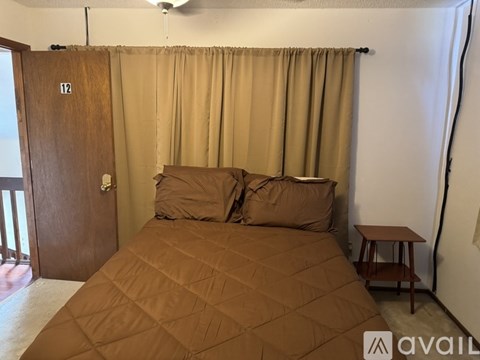 A bedroom with a bed, a small table, and a ceiling fan.