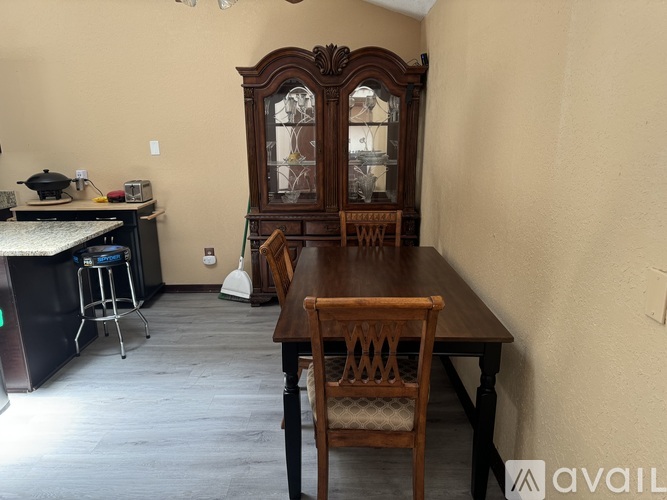 A dining room with a wooden table and chairs and a large wooden cabinet.