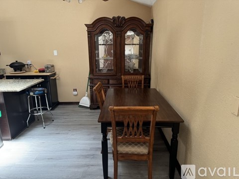 A dining room with a wooden table and chairs and a large wooden cabinet.
