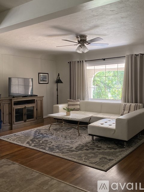 A living room with a white couch and a rug.