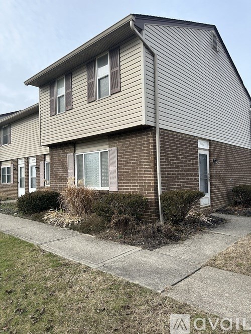 A two-story house with a grey roof and brick exterior.