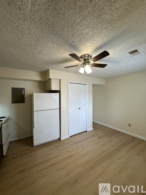A room with a ceiling fan and a white refrigerator.