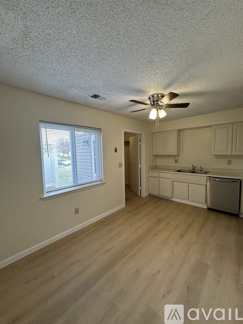 A room with a ceiling fan and wooden flooring.