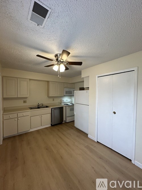 A kitchen with white cabinets and a wooden floor.