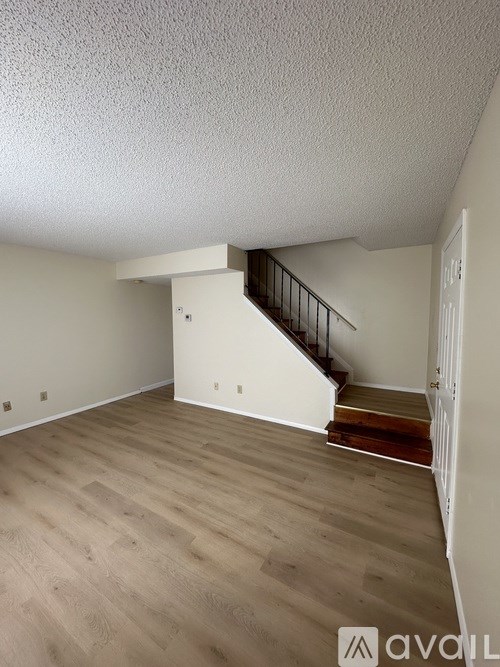 A room with wooden flooring and a staircase with a metal railing.