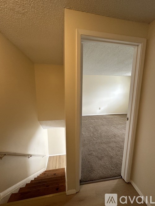A hallway with a carpeted floor and a staircase leading to the second floor.