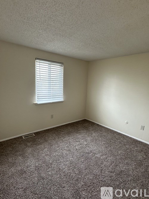 A room with a carpeted floor and a window with blinds.